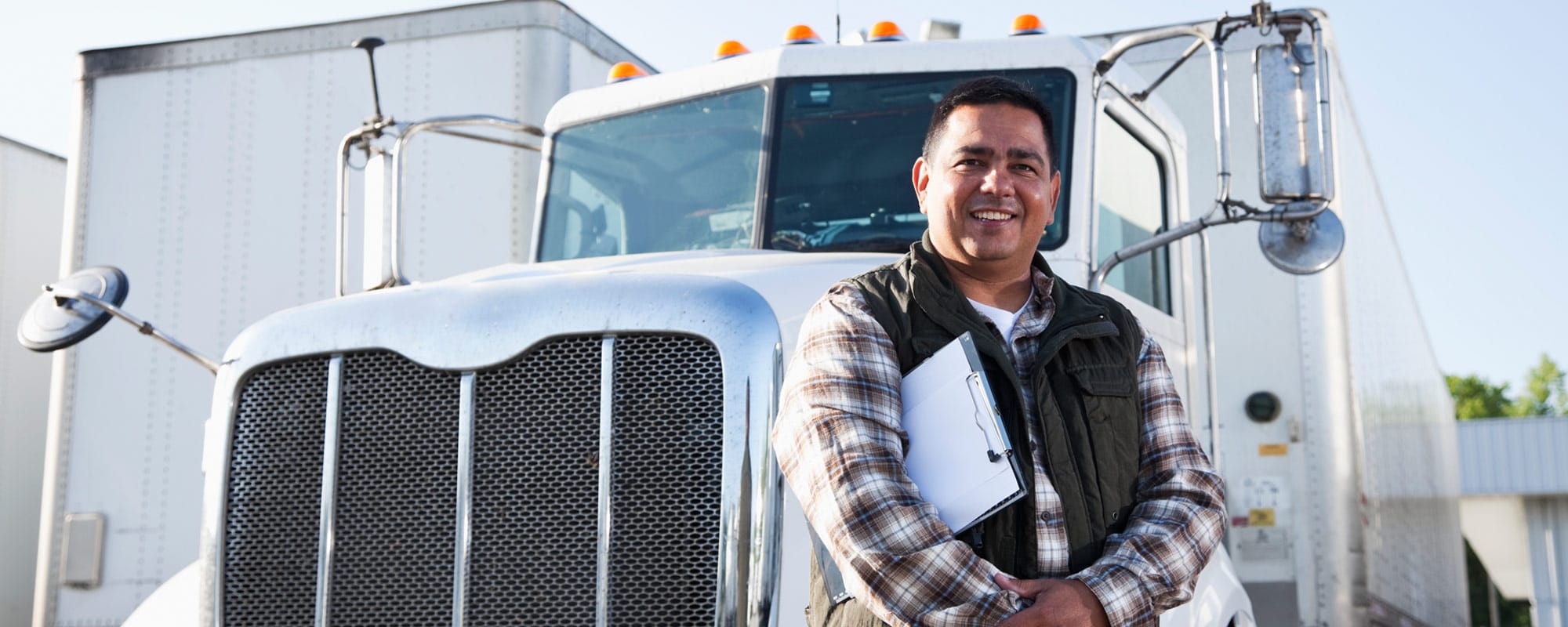 Image of smiling man standing in front of his tractor-trailer